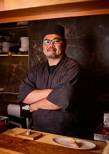 Master sushi chef smiling at his omakase counter