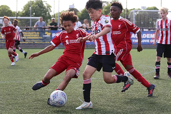 サッカーユニフォームを着た少年たちが試合会場で争う